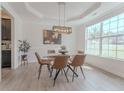 Elegant dining room features modern chandelier, tray ceiling, and large windows for natural light at 80 Pedley Pl, Cameron, NC 28326