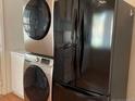 Modern kitchen featuring stainless steel washer-dryer set and a sleek, black, Whirlpool refrigerator at 1113 Midland Ter, Durham, NC 27704