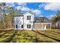Exterior view of a white home's backyard featuring a covered patio and a lush green lawn at 298 Dove Rd, Cameron, NC 28326