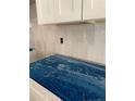 Close-up of a blue-covered countertop with white cabinets and white tile backsplash at 298 Dove Rd, Cameron, NC 28326
