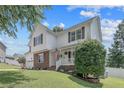 Angle view of lovely two-story home with landscaped yard, green lawn, brick accents, and cozy front porch with American flag at 43 Ambrose Pt, Cameron, NC 28326