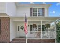 Inviting front porch with brick accents, patriotic flag, hanging flower baskets, and rocking chairs at 43 Ambrose Pt, Cameron, NC 28326