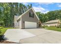 Side view of a two-car garage with gray siding, a long driveway, and mature trees in the background at 787 Cashmere Ct, Sanford, NC 27332