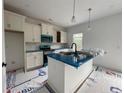 Bright kitchen features an island, modern lighting, stainless appliances, and white cabinets at 138 Travelers Way, Lillington, NC 27546