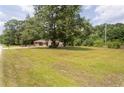 Quaint brick home with a large lawn and mature trees viewed from across the road at 5824 Adcock Rd, Holly Springs, NC 27540