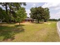 Quaint brick home with a large lawn and mature trees by the roadside at 5824 Adcock Rd, Holly Springs, NC 27540