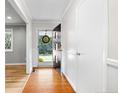 Entry way and hallway with white walls, wood floors, and black door and trim at 602 Canterbury Rd, Sanford, NC 27330