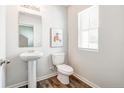 Well-lit half bathroom featuring wood-look floors, pedestal sink and ample natural light at 560 Stadium Drive, Cameron, NC 28326