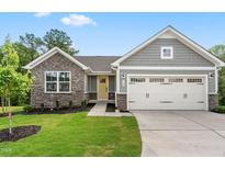 Charming home with a two-car garage, stone accents, manicured lawn and a bright yellow front door at 164 Clove Hitch Ln, Fuquay Varina, NC 27526