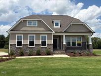 Charming single-Gathering home featuring stone accents, well-manicured lawn, and inviting front porch at 103 Sage Ln # 009, Four Oaks, NC 27524