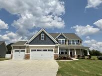 Beautiful two-story home featuring a three-car garage and manicured lawn under a partly cloudy sky at 234 Crystal Springs Way, Benson, NC 27504