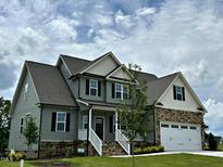 Charming two-story home featuring stone accents, gray siding, attached garage, and a well-manicured lawn at 27 Prency Ln, Middlesex, NC 27557