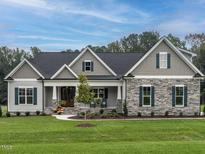 Charming home with stone accents, symmetrical design, and a welcoming front porch at 100 Old Garden Ln, Youngsville, NC 27596