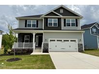 Two-story home featuring light gray siding, a two-car garage, and a welcoming front porch at 152 Southern Estates Dr, Sanford, NC 27330