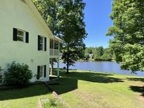 A white brick home with a gorgeous green lawn overlooking the serene lake view at 3309 Westcott Cir, Sanford, NC 27330