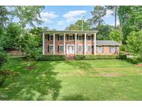 Stately brick home featuring a symmetrical facade, grand columns, and a beautifully manicured front lawn at 5513 Parkwood Dr, Raleigh, NC 27612