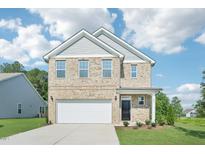 Two-story brick home boasts an attached two-car garage, manicured lawn, and inviting front porch at 401 Winding Creek Dr, Lillington, NC 27546