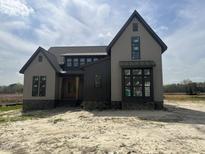 New construction exterior showcasing gray siding, black trim, and stone accents under a cloudy sky at 4905 Hidden Pasture Way, Zebulon, NC 27597