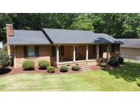 Charming brick home featuring a covered front porch and meticulously manicured landscaping at 305 Deerfield Dr, Clayton, NC 27527