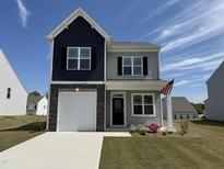 Charming two-story home featuring a stone accent, garage, and manicured lawn with an American flag at 32 Furley St., Homesite 53, Sanford, NC 27330
