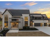 Stunning modern home boasts a brick and stone exterior, large windows, manicured landscaping, and a multi-car garage at 9009 Meadow Pointe Ct, Wake Forest, NC 27587