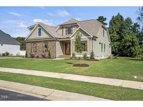Charming home featuring a beautifully landscaped lawn and a mix of stone and siding exterior at 112 Lambert Ln, Fuquay Varina, NC 27526