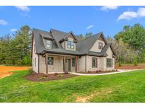 Charming brick home featuring a covered front porch, gable roof, and beautifully landscaped yard at 3402 St Barts Pl, Mebane, NC 27302
