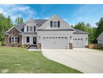 Two-story house with stone and white siding, three-car garage, and manicured lawn at 21 Walnut Hall Ct, Selma, NC 27576