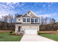 Charming two-story home featuring a well-manicured lawn and attached two-car garage at 176 Van Winkle St, Lillington, NC 27546