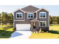 Charming two-story home with gray siding, a white garage door, and a well-manicured front lawn at 592 Barbour Farm Ln, Four Oaks, NC 27524