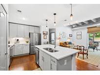 Bright, open kitchen with stainless steel appliances, island with sink, and modern pendant lighting at 1300 St Marys St # 208, Raleigh, NC 27605