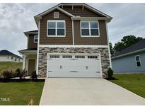 Two-story home with stone accents and a large white two car garage door and concrete driveway at 316 Bishop Ln, Sanford, NC 27330