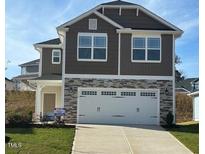 Charming two-story home with a two-car garage and stone accents, complemented by a well-maintained front lawn at 316 Bishop Ln, Sanford, NC 27330