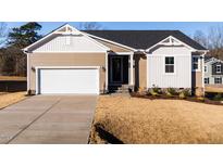 Two-story house with beige siding, white accents, and a two-car garage at 411 Fast Pitch Ln, Four Oaks, NC 27524