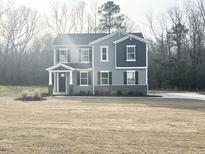 New construction two-story home features stone accents, a covered porch, and gray siding at 427 Fast Pitch Ln, Four Oaks, NC 27524