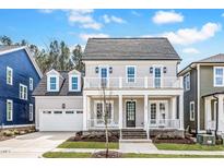 Charming two-story home with a welcoming front porch and balcony, complemented by lush landscaping at 809 St Charles St, Durham, NC 27713