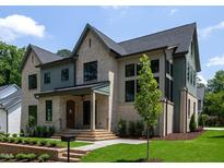 Elegant two-story home featuring a brick facade, manicured lawn, and stylish architectural details at 1000 Marilyn Dr, Raleigh, NC 27607