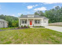 Charming one-story home featuring a red front door, gray siding, and attached garage at 148 Harmony Trl, Broadway, NC 27505