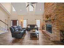 Bright living room features a stone fireplace, hardwood floors, and comfortable black leather furniture at 2674 Stanton Hill Rd, Cameron, NC 28326