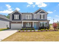 Beautiful two-story home with stone accents, a covered front porch, attached garage, and manicured lawn at 541 Henham Way, Zebulon, NC 27597