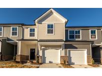 Modern townhome exterior featuring neutral siding, attached garages, and well-maintained landscaping under a bright blue sky at 567 Marthas Vw Way, Wake Forest, NC 27587