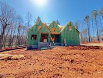 New construction home featuring the frame of a charming house under a clear blue sky surrounded by dirt and trees at 111 Gaines Trail, Pittsboro, NC 27312