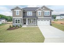 Charming two-story home with a well-manicured lawn and a two-car garage showcasing its appealing curb appeal at 136 Newport Lndg, Garner, NC 27529