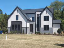 Striking modern farmhouse with crisp white siding, black accents, and manicured lawn at 5812 Shawood Dr, Raleigh, NC 27609