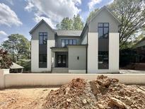 Modern two-story home featuring a combination of gray and white brick exterior with large windows and professional landscaping at 5208 Knollwood Rd, Raleigh, NC 27609