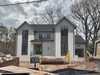 New construction gray and white two-story home boasts modern design, black trim windows, and an attached garage at 5208 Knollwood Rd, Raleigh, NC 27609