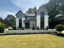 Striking two-story home featuring a manicured lawn, modern design, and professionally landscaped yard at 5208 Knollwood Rd, Raleigh, NC 27609