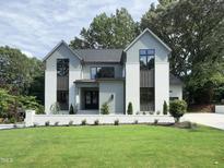 Beautiful two-story home featuring a well-manicured lawn and a white brick retaining wall at 5208 Knollwood Rd, Raleigh, NC 27609