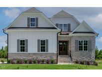 Inviting two-story home featuring stone accents, vertical siding, and a beautifully landscaped front yard at 55 Harvest View Way, Franklinton, NC 27525