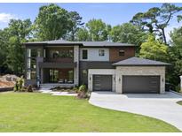 Modern two story home boasts a manicured lawn, two car garage, and stone and wood exterior at 4123 Rockingham Dr, Raleigh, NC 27609